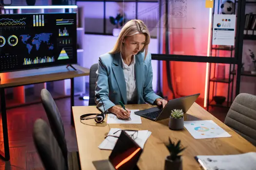 image of a lady writing and reading from a laptop computer