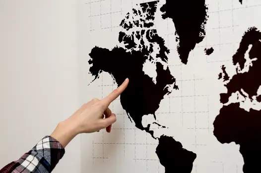 Black Map of the world on a white background with someone pointing at it