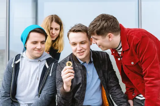 A young man showing a physical bitcoin to his friends