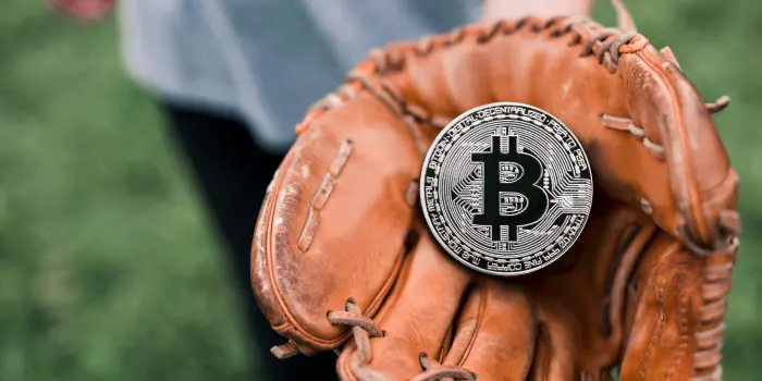 Man holding a baseball glove with a big bitcoin in it